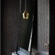 Badrumsinspiration - Liten toalett med svart knappmosaik, stående spegel och mässinglampa av Alvar Aalto för Artek