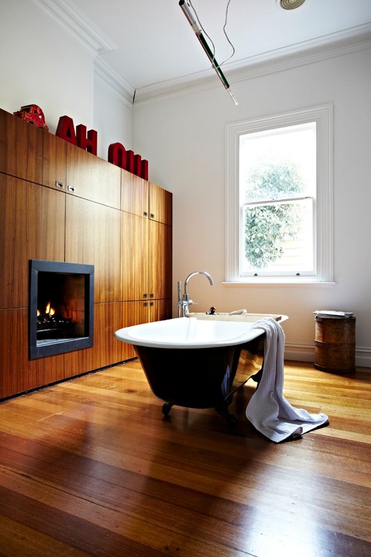 Badrumsinspiration - Vitt 10x20 kakel med svart fog, kaklad hylla, kakellist, badrumslampor på spegel och svart tassbadkar i badrum med teakgolv i Australien 