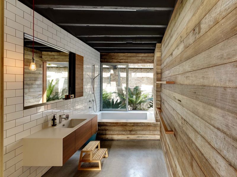 Badrumsinspiration - Badrum med vitt 10x20 kakel i halvförband, slitet trä, inbyggt badkar med träfront, betonggolv