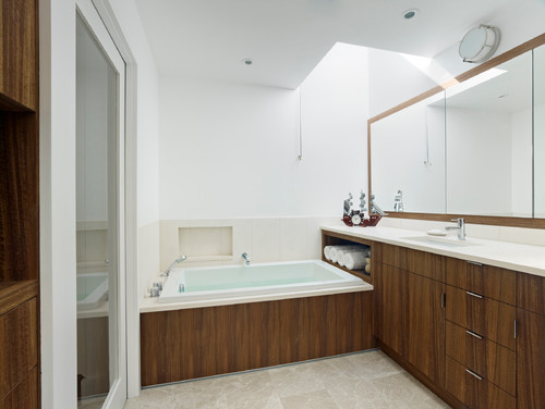 Modernt badrum med teak och inbyggt badkar.