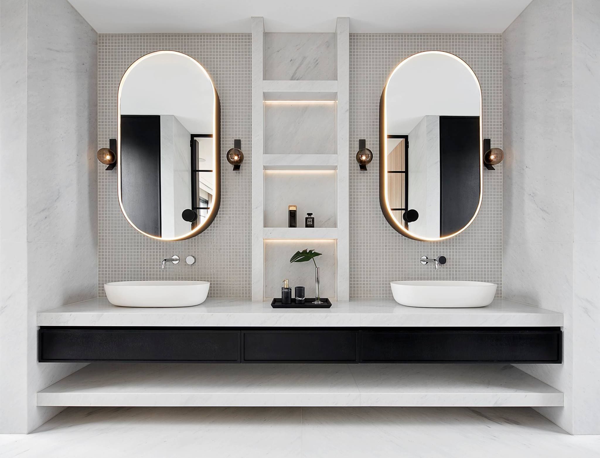 Modernt badrum med snygga spegelskåp, badrumslampor och mosaik.