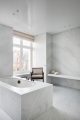 Badrumsinspiration - Minimalistiskt badrum av Nicolas Schuybroek i carrara med inbyggt badkar, stol Chandigarh av Pierre Jeanneret.
