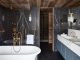 badrumsinspiration lyxigt badrum i alperna svart marmor guld stenhandfat badrumslampa handdukstork chalet gstaad design Humbert Poyet foto Francis Amiand badrumsdrommar