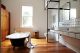Badrumsinspiration - Vitt 10x20 kakel med svart fog, kaklad hylla, kakellist, badrumslampor på spegel och svart tassbadkar i badrum med teakgolv i Australien