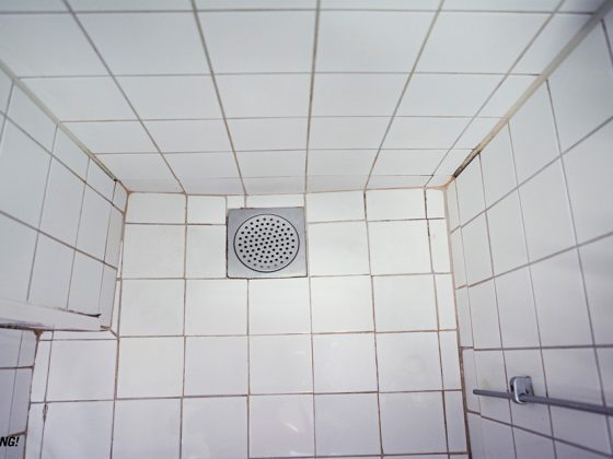 Badrumsinspiration - FÖRE - Litet badrum med vitt15x15, mörk fog och mässing på Tavastgatan i Stockholm