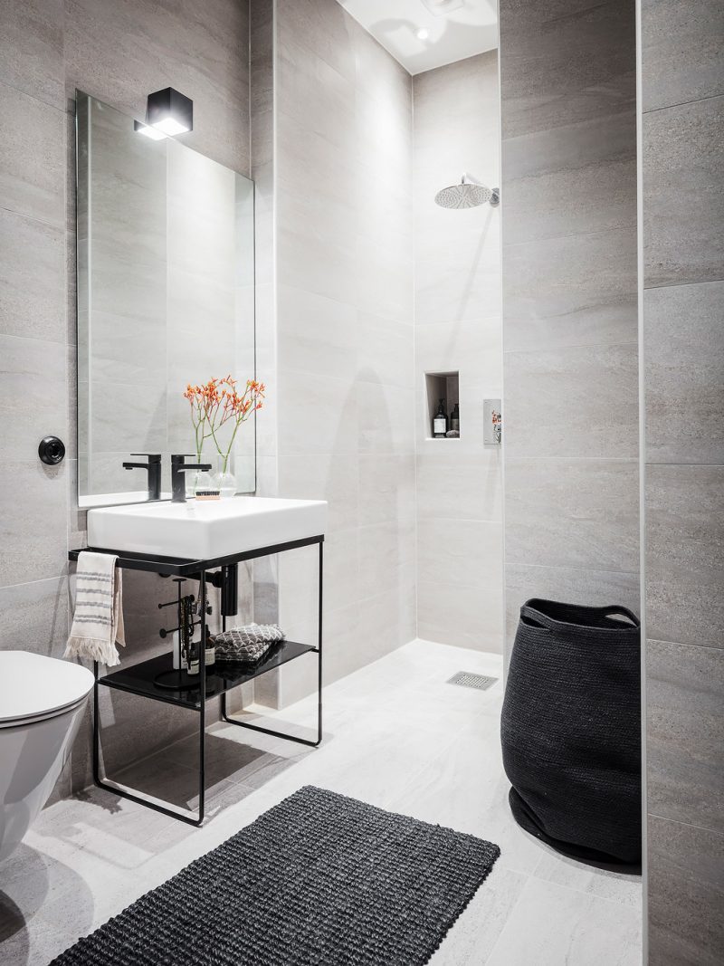 Badrumsinpiration - Stora plattor i litet badrum, kakellist på ytterhörn och svart blandare och tvättställ med benställning